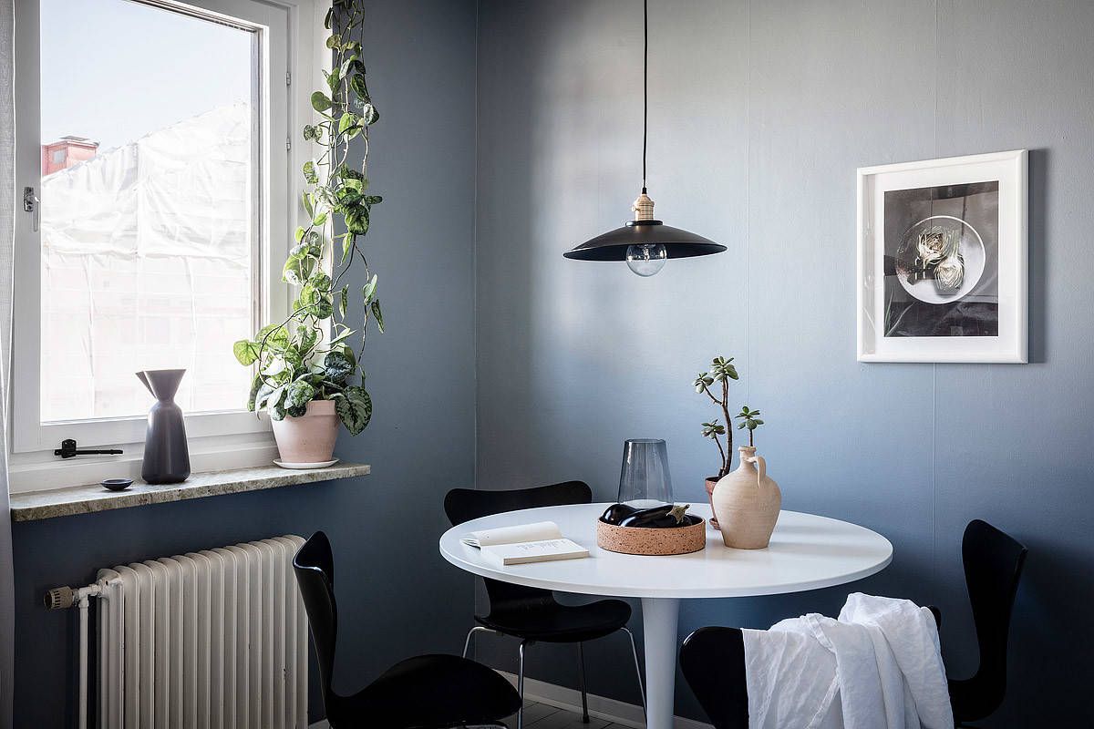 Pendant and chairs add black to the small Scandinavian dining space with blue backdrop