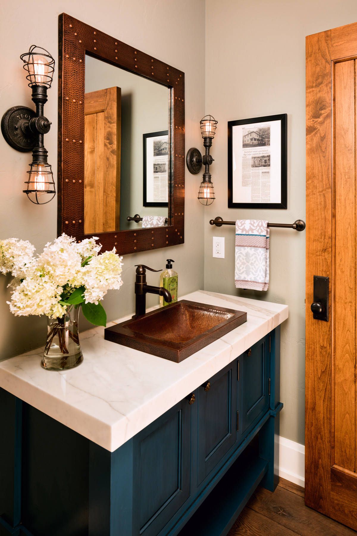 Posh vanity in blue along with sconce lighting for the farmhouse style powder room