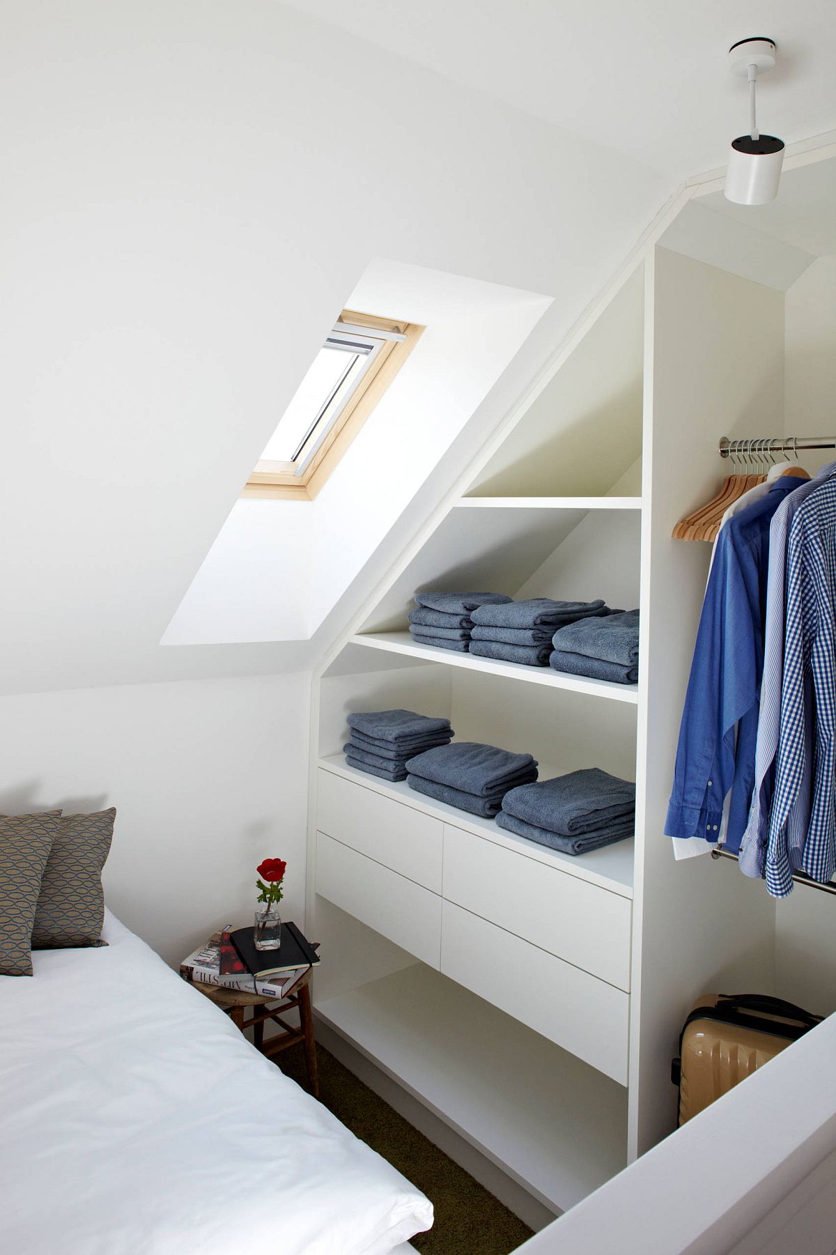 Small attic bedroom closet with neatly folded clothes and lots of shelf space