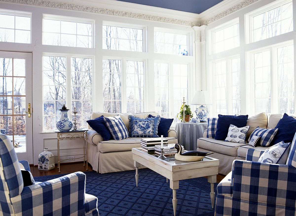 Sofa covers and pillows bring blue checkered pattern to the spacious sunroom in white