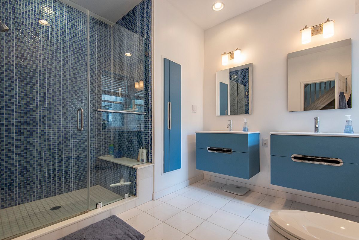 Spacious white contemporary bathroom with double blue vanities, integrated sound system and lovely automated lights