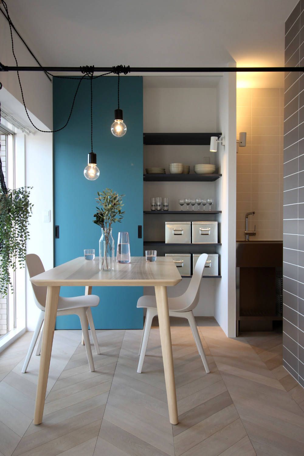 Storage wall with sliding door in the backdrop adds blue to the small dining room