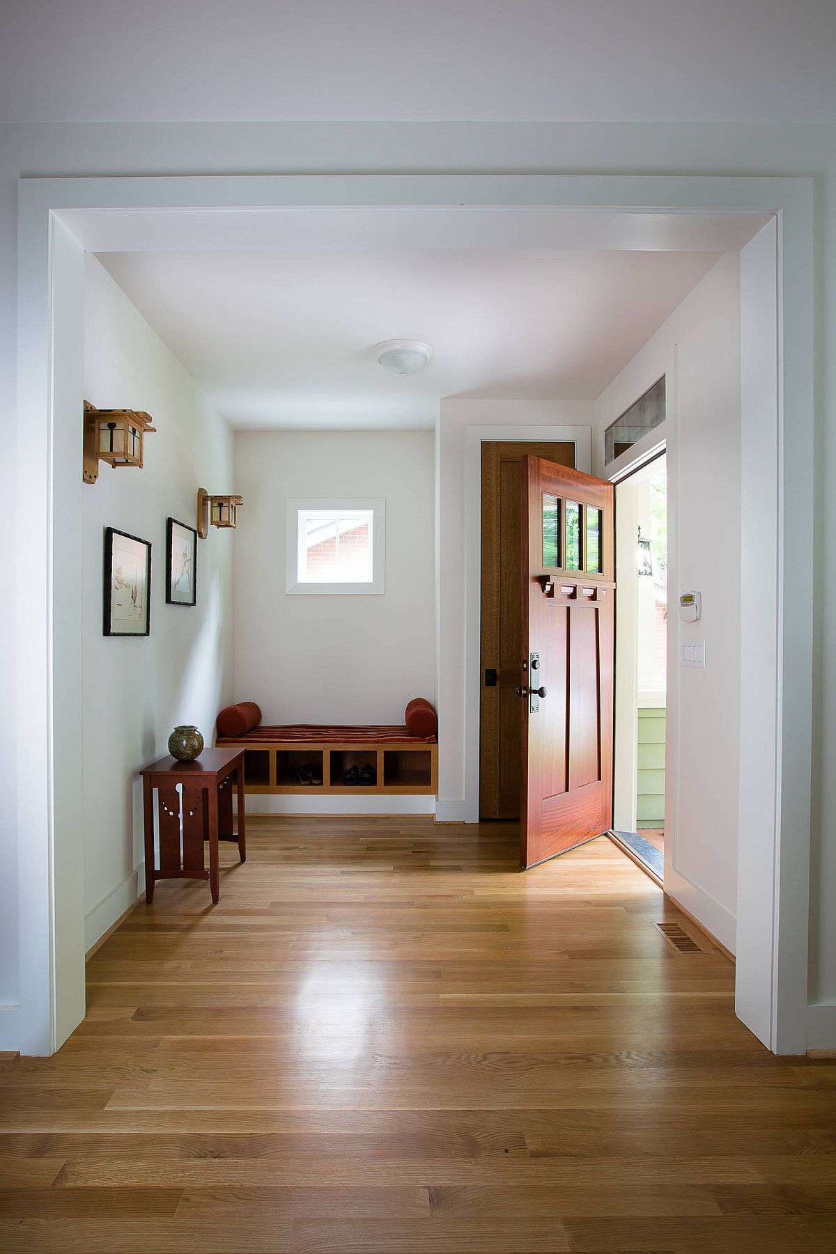 Unassuming entry room in white with functional wooden decor that offers storage space