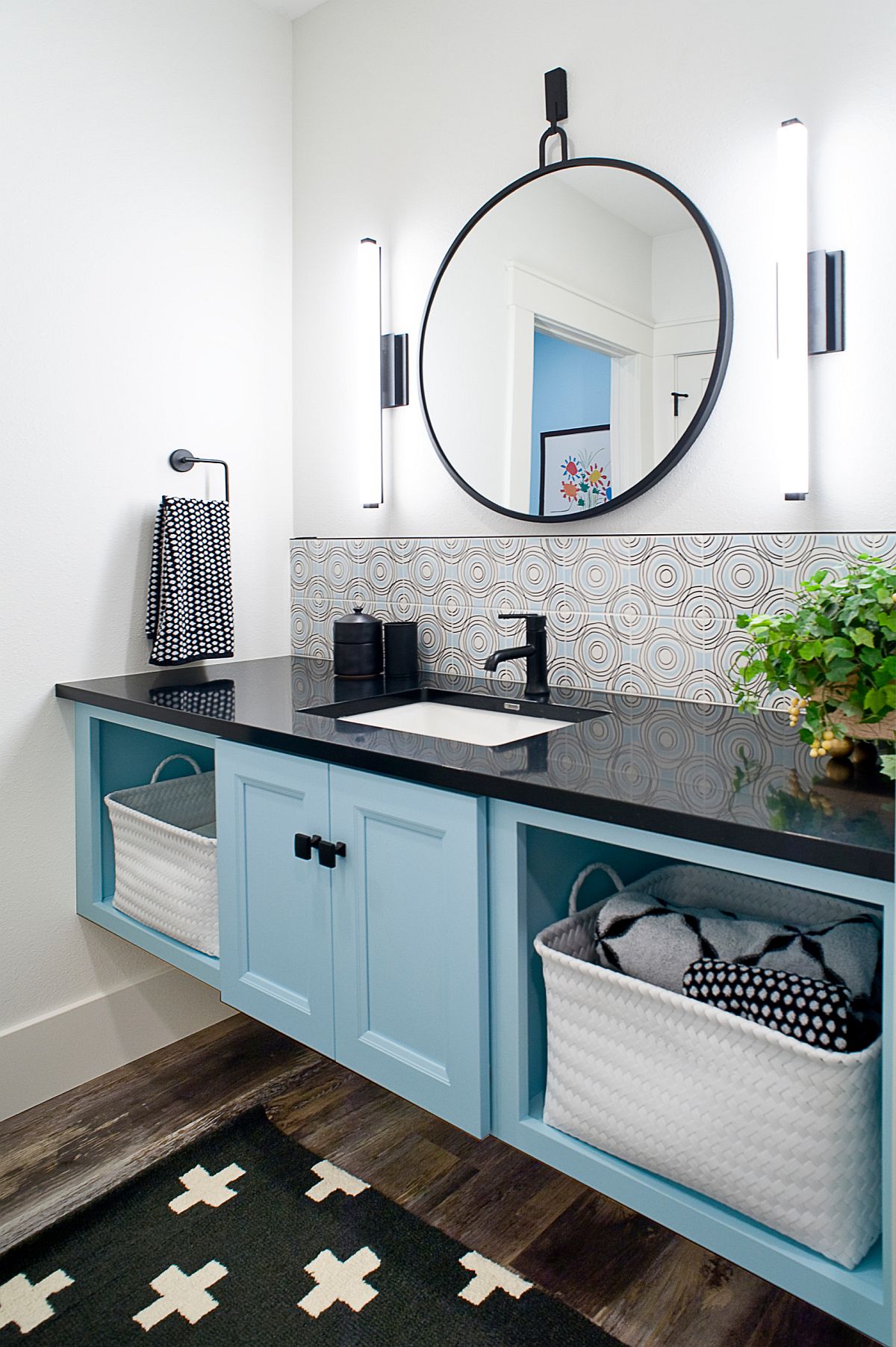 Vanity in lighter shade of blue with open shelving and black countertop for the farmhouse style bathroom