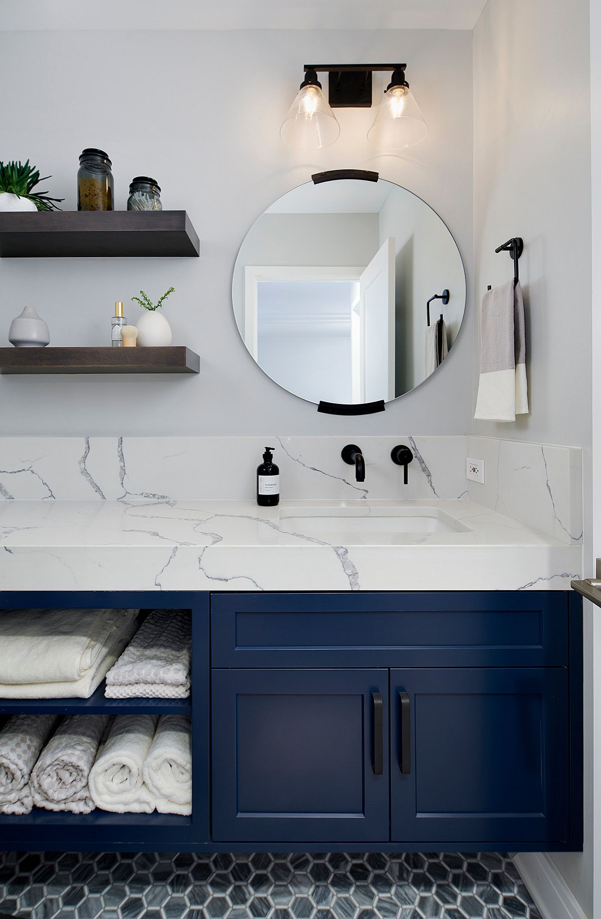 White countertops, walls and lovely lighting accentuate the appeal of the dark blue vanity