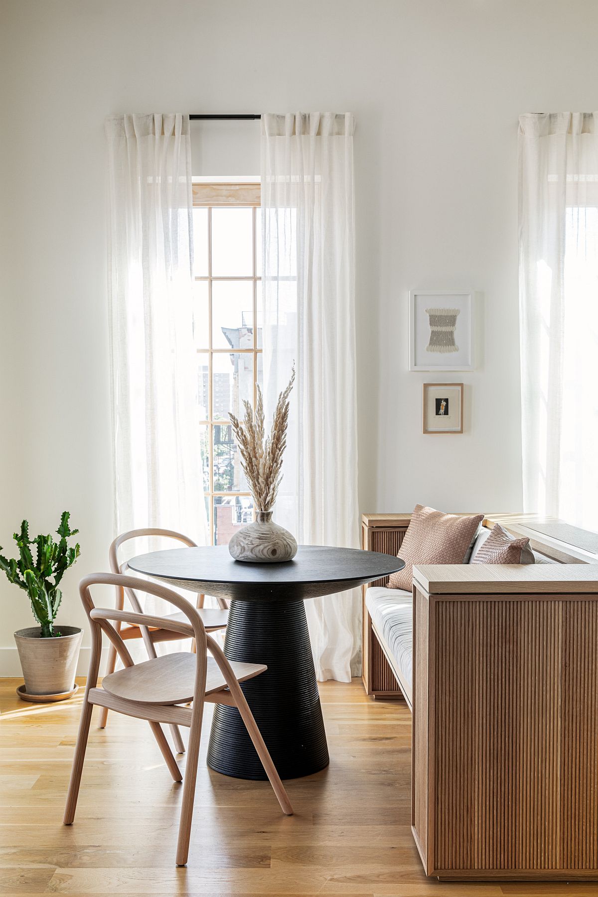 Wooden bench adds additional setaing space to the small dining area with black round dining table