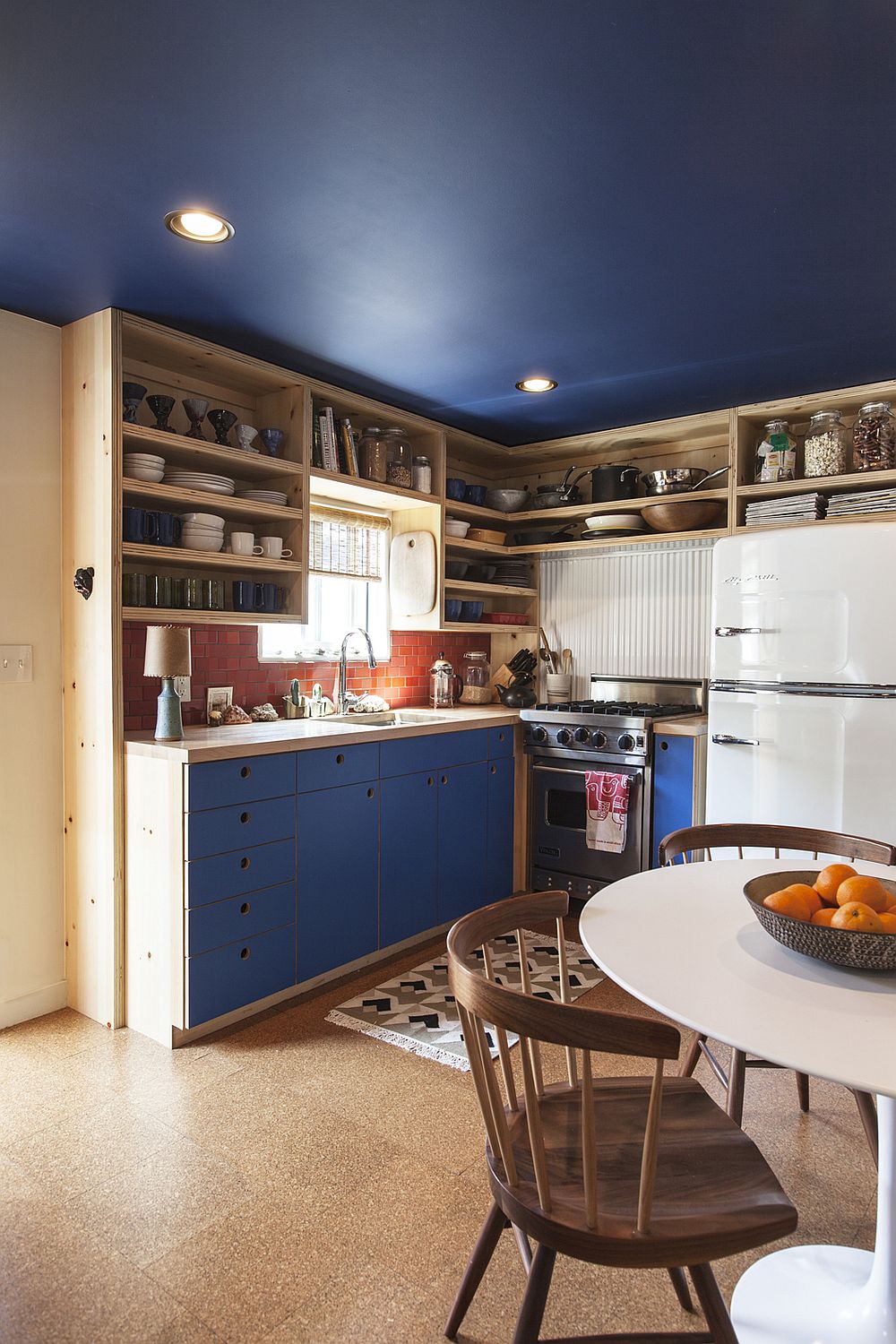Blue cabinets in the kitchen add to the colorful appeal of the trailer home with a striking blue ceiling