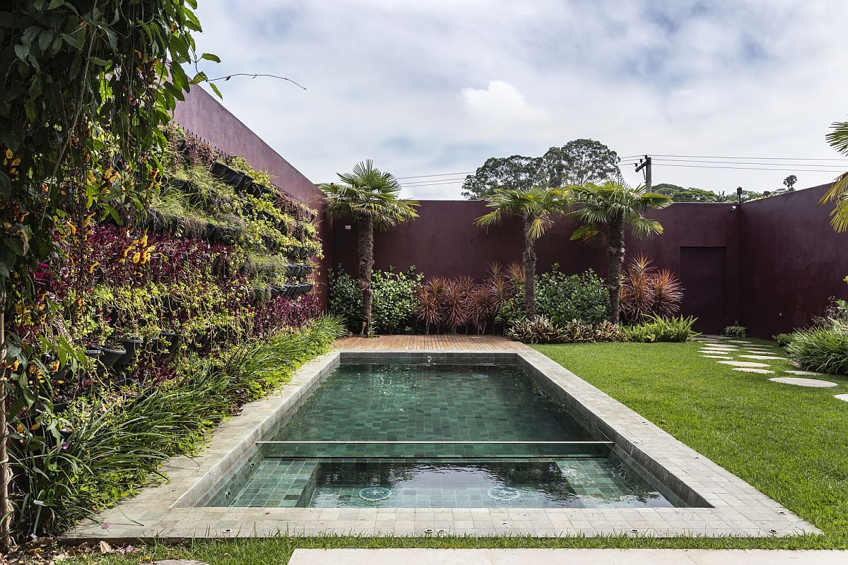 Colorful walls, greenery and a lovely pool shape the rear garden of the house