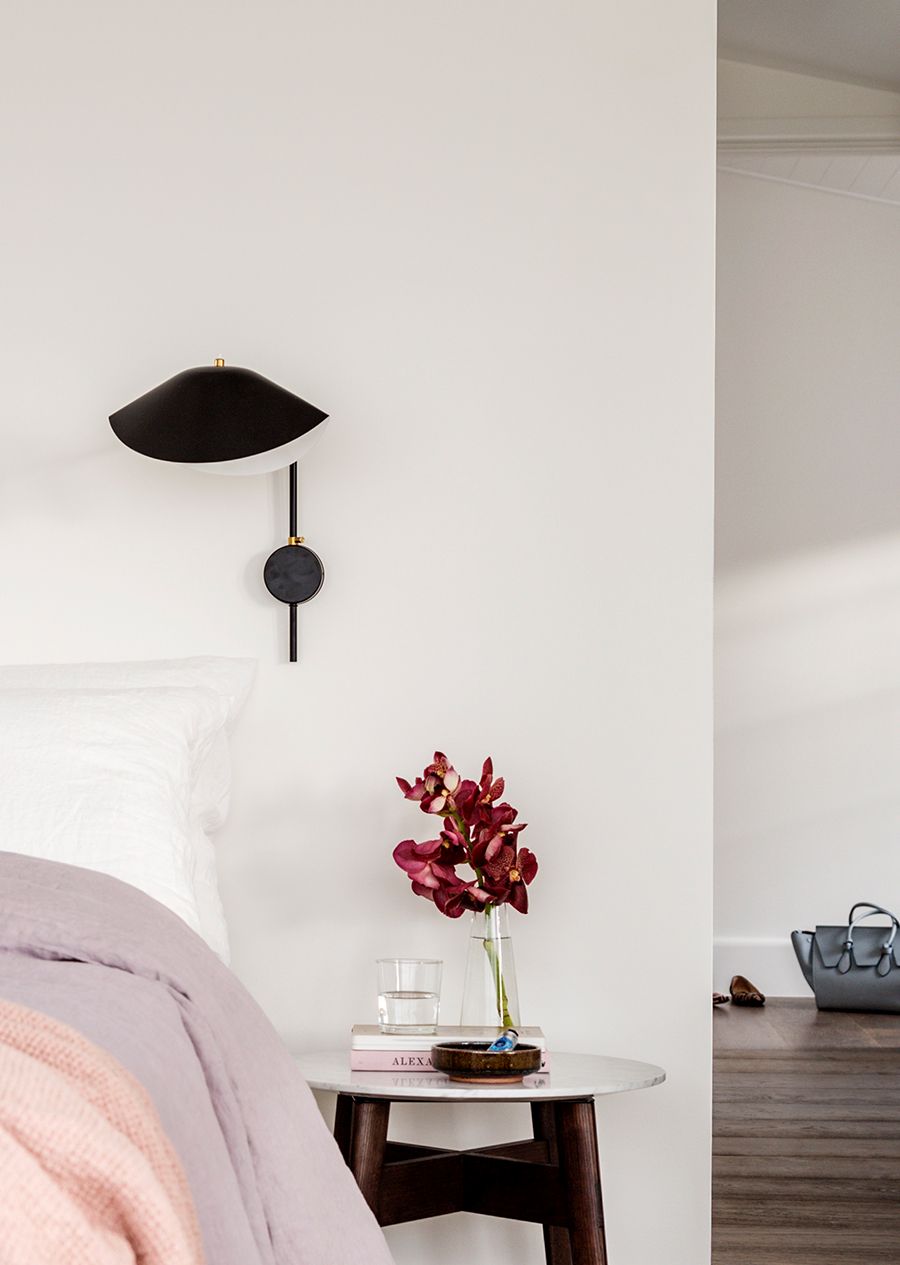 Decorating the small space next to the bed with a tiny side table and sconce light