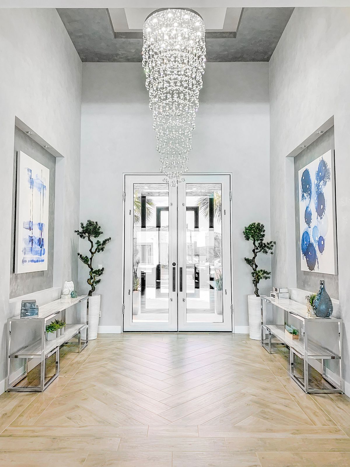 Gorgeous-cascading-chandelier-lights-up-this-large-entry-in-white-with-greenery-and-pops-of-blue-94936