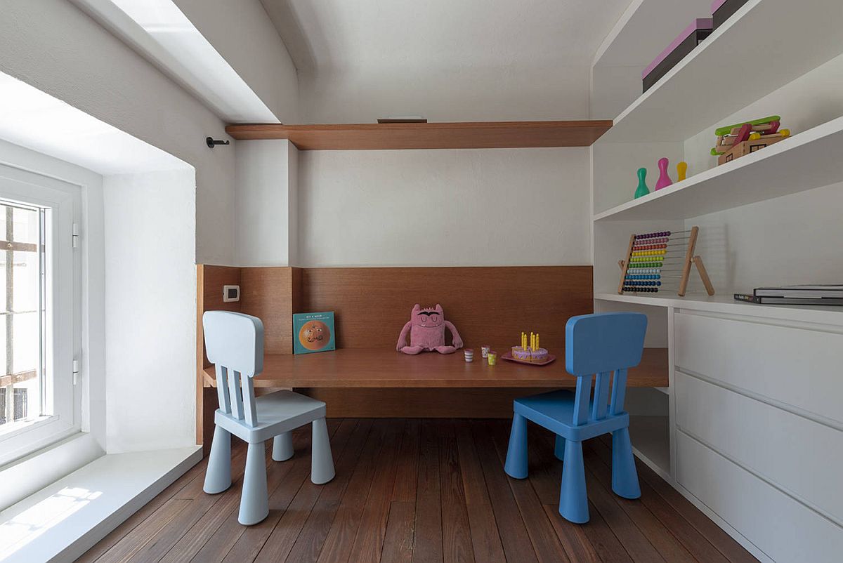 Minimal play area inside the small kids' bedroom with a couple of chairs, wooden shelves and ample space