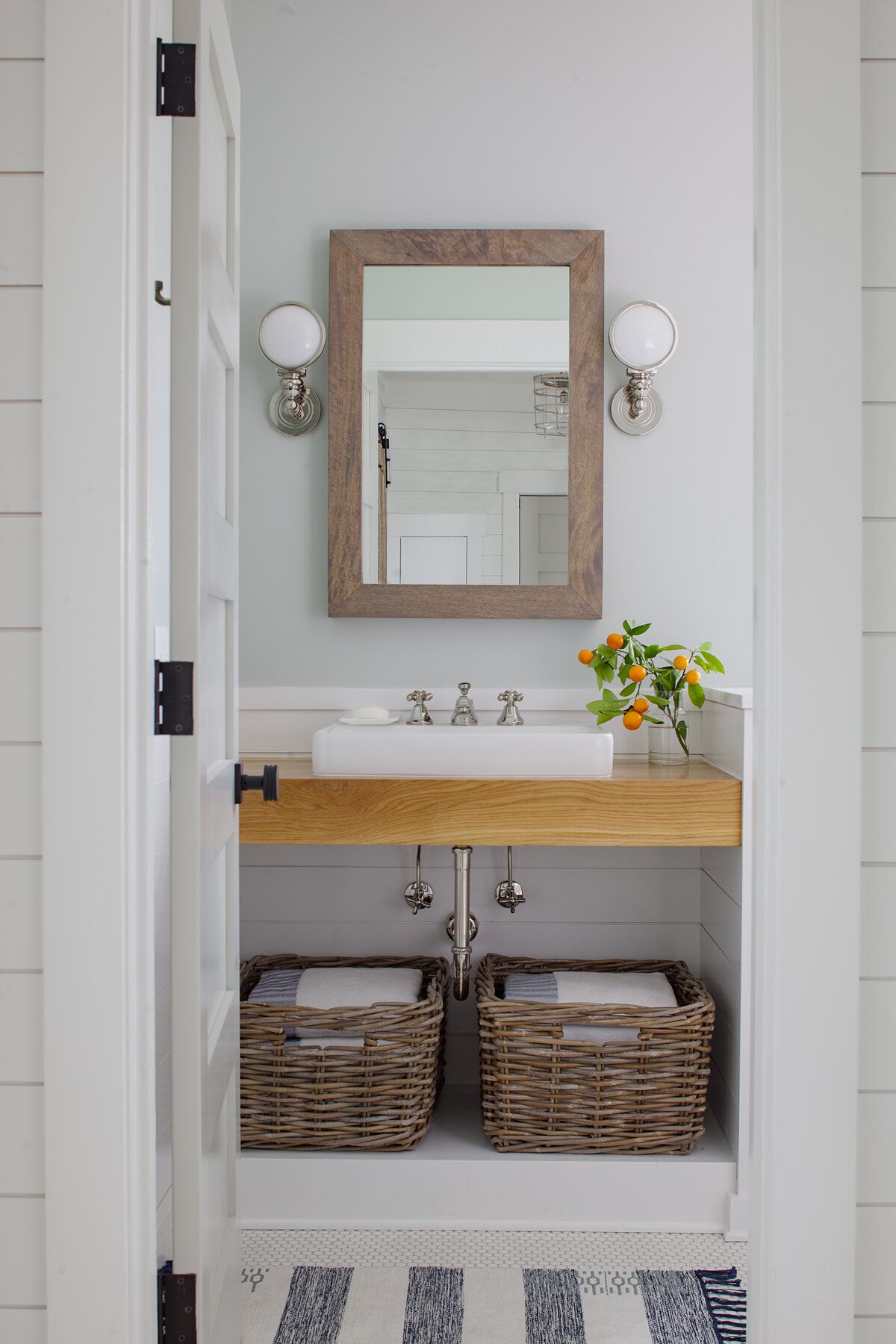 Modern beach style bathroom with thin wooden vanity and a couple of baskets for storage