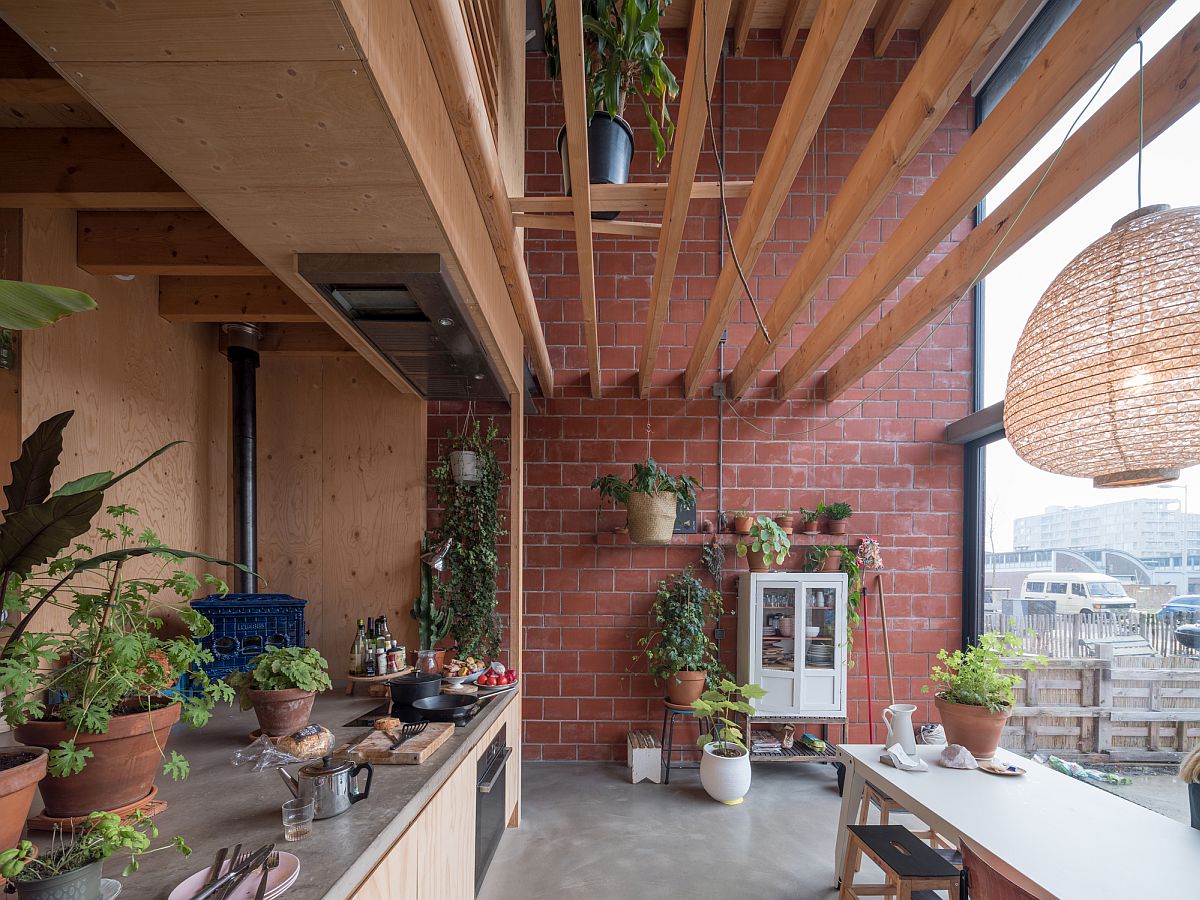 Pleasing blend of warm red terracotta bricks and wood in the kitchen with a metal door that can be lifted up