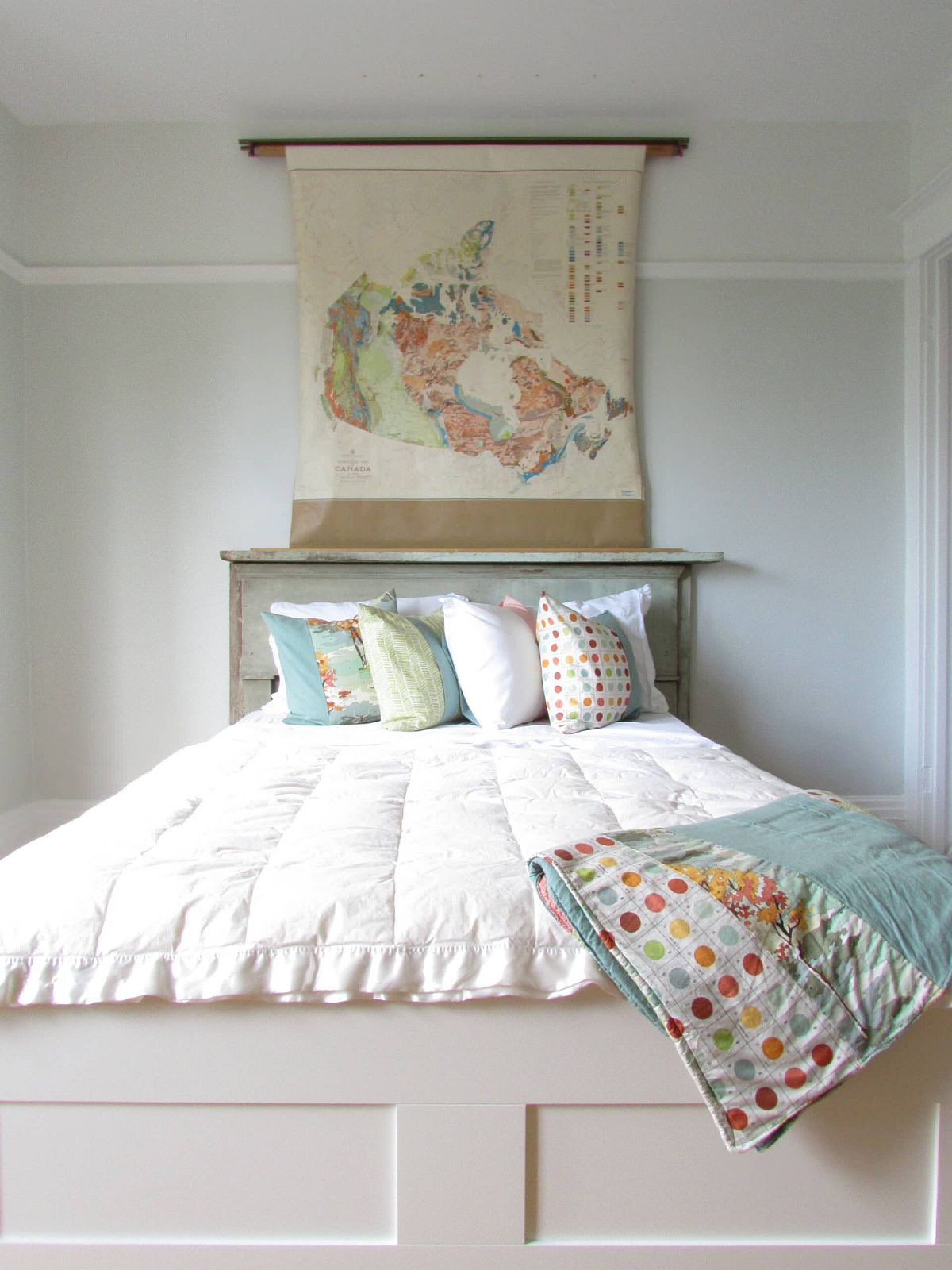 Shabby chic bedroom in white where the map above the headboard usher in color