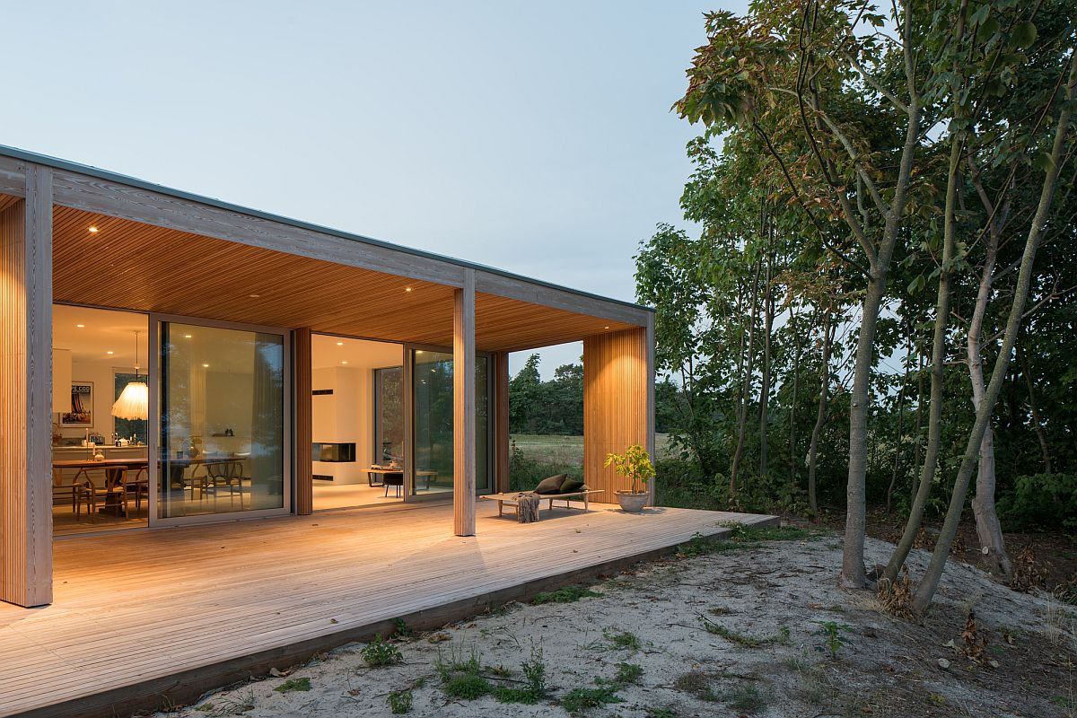 Sliding glass doors connect the interior of the summerhouse with the sweeping wooden deck