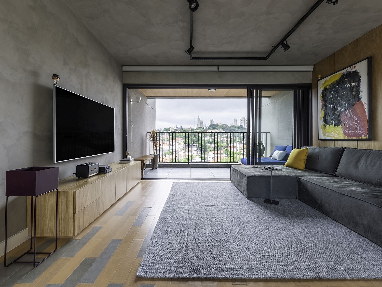 Spacious living room with wooden floor and concrete ceiling and walls