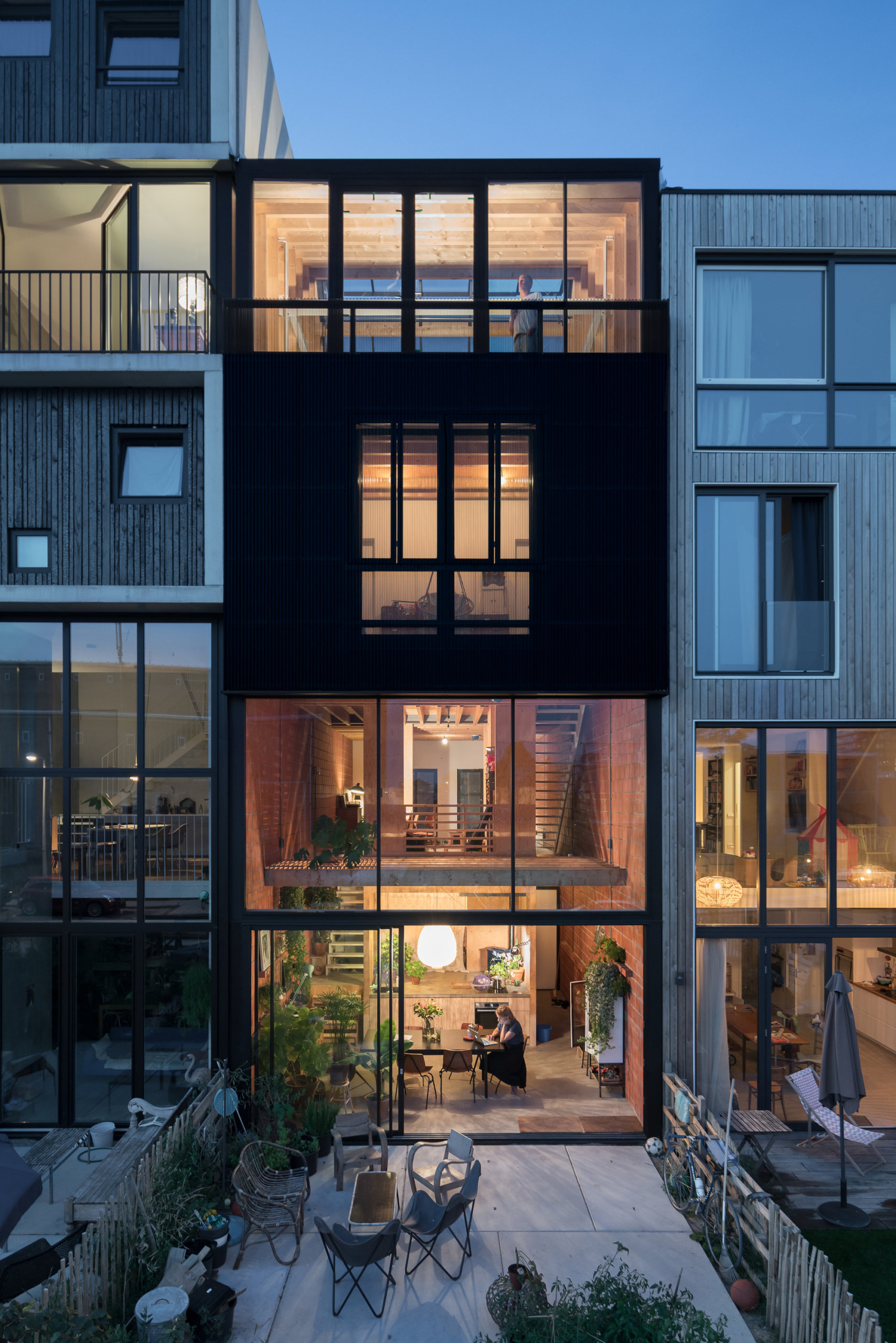 Striking black, perforated corrugated sheeting shapes the exterior of the house as lighting illuminates it elegantly