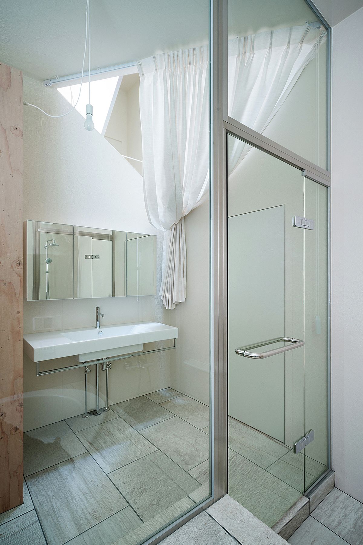 Triangular cut-out in the ceiling brings natural light into the small bathroom and shower area