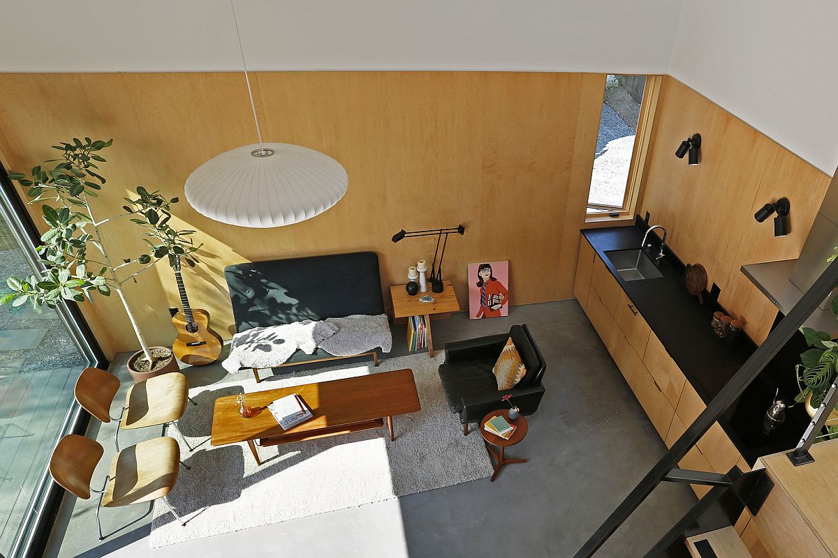 View of the small living area with wooden panel-covered walls from the loft level of the backyard house