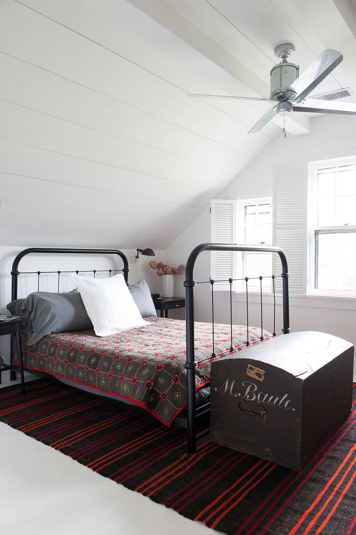 Attic level bedroom of the New York home with modern farmhouse style and a bright rug