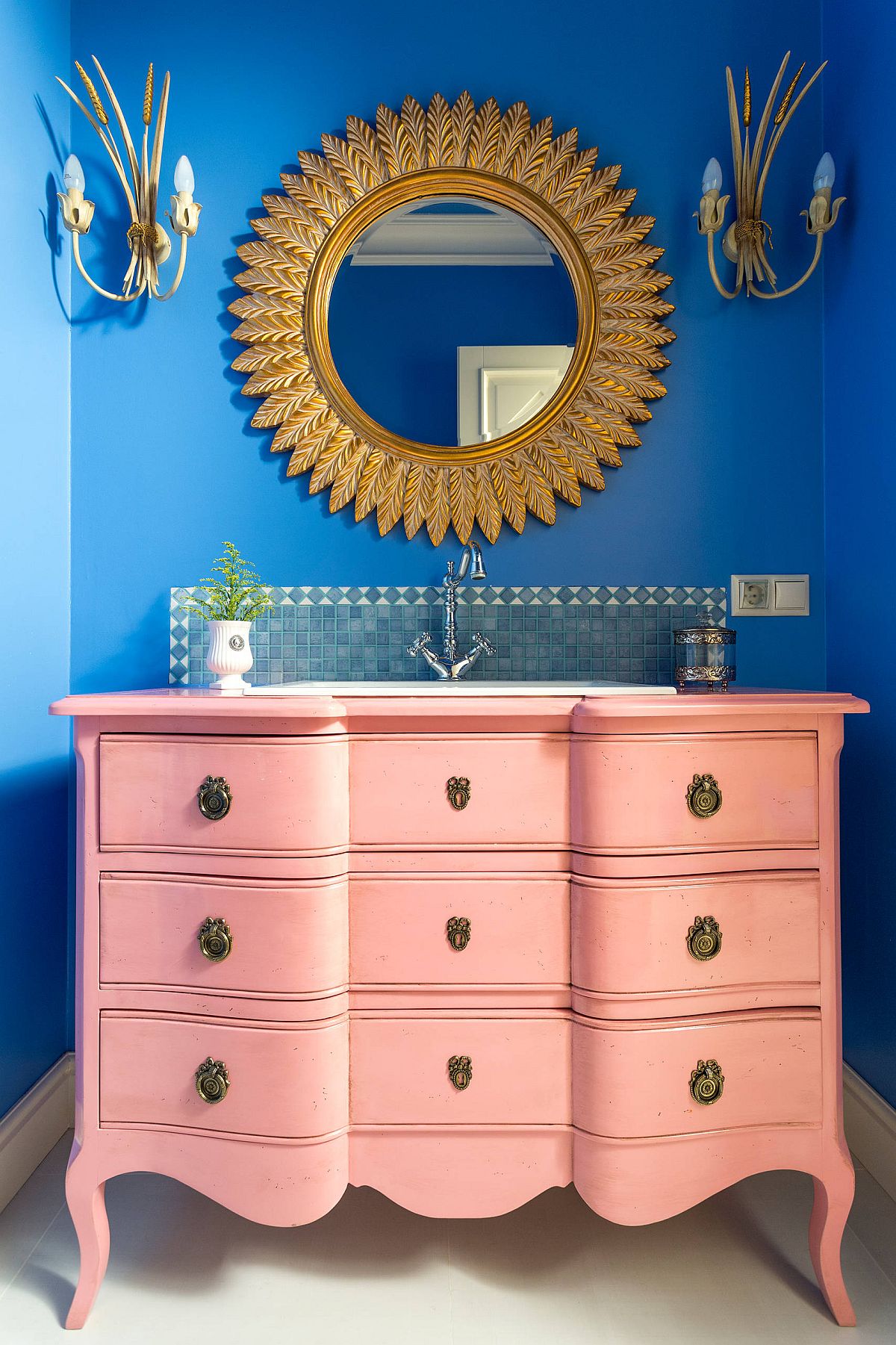 Awesome bathroom in blue with a light pink vanity and a dazzling gold mirror