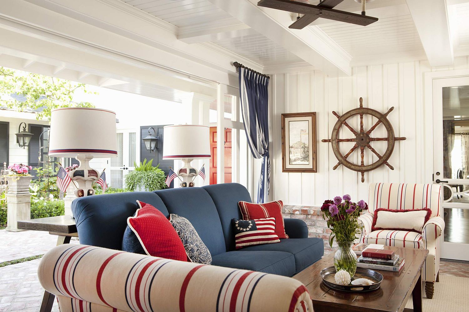 Beautiful beach style porch of San Deigo home with bright blue couch and striped chairs in cream, blue and red