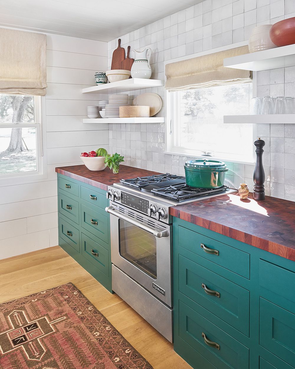 Butcher block kitchen coutertops combined with teal cabinets and white tiled backsplash