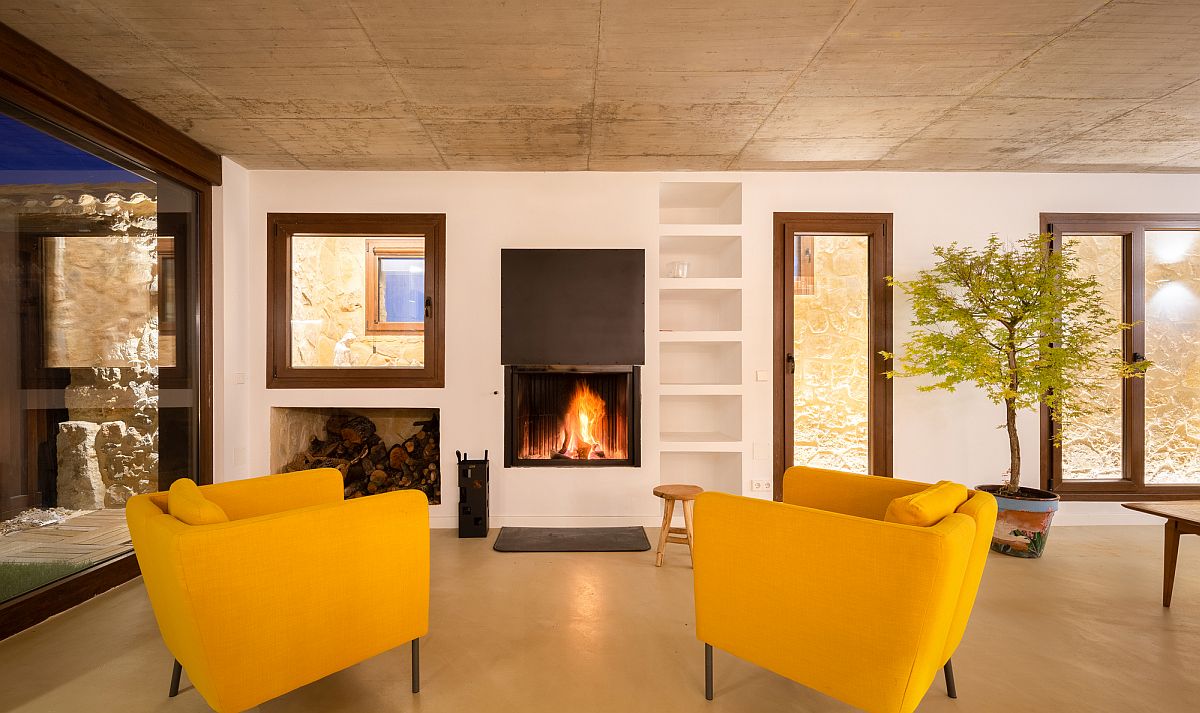Contemporary living area of the house with bright yellow chairs and a fireplace