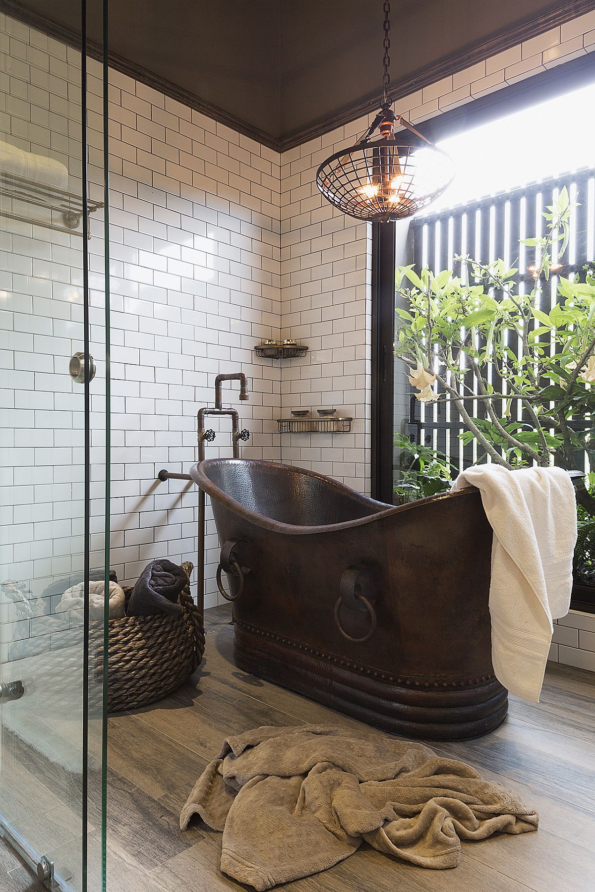 Copper bathtub along with glass walls and greenery adds uniqueness to the bathroom