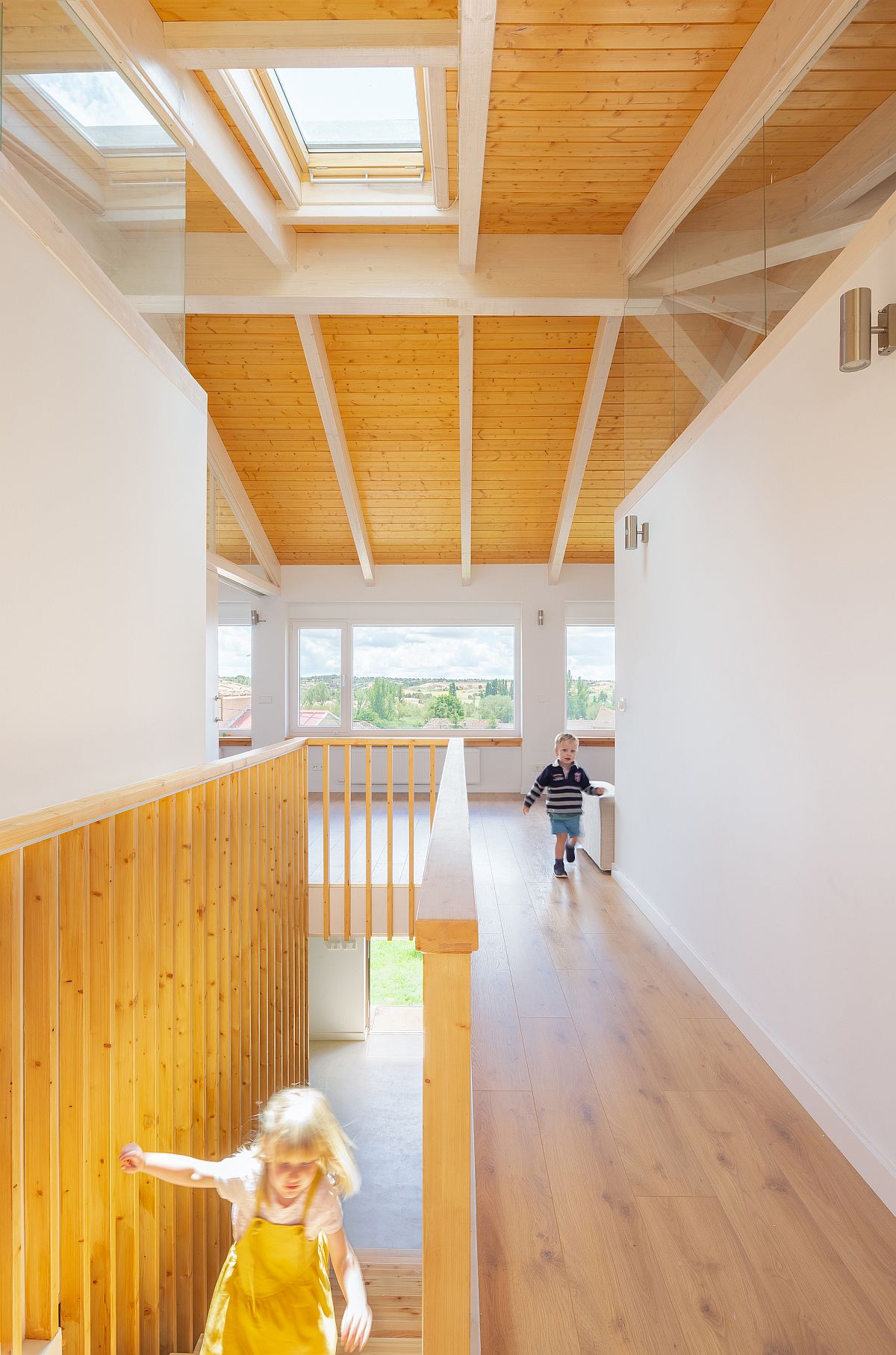 Crisscrossing white ceiling beams give the upper level of the house a unique look