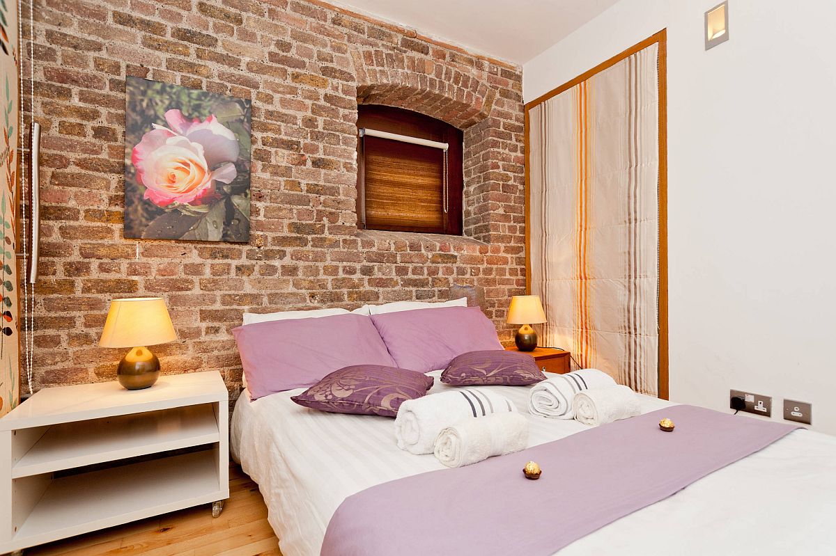Custom interior of small eclectic bedroom with lovely brick wall backdrop