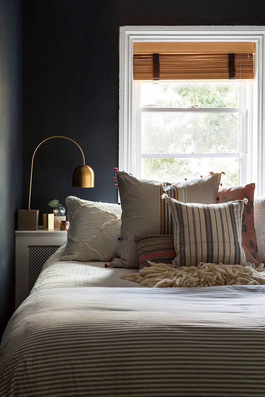 Dark gray backdrop in the small bedroom gives it a polsihed urbane style