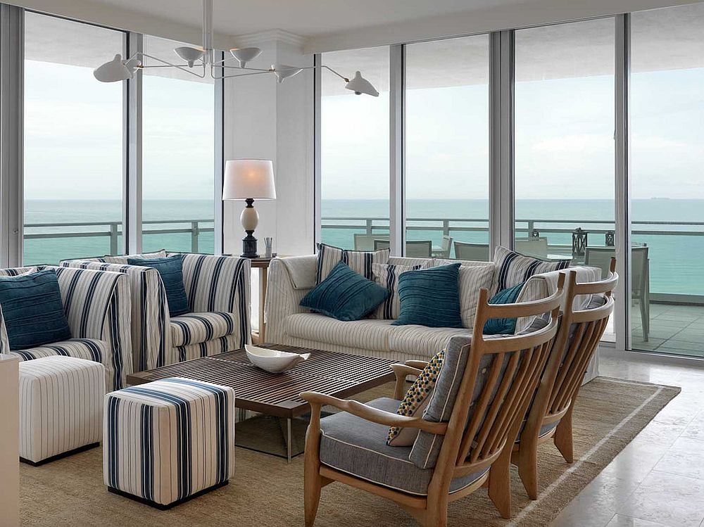 Dashing striped ottomans coupled with chairs in the polished contemporary living area with sea views