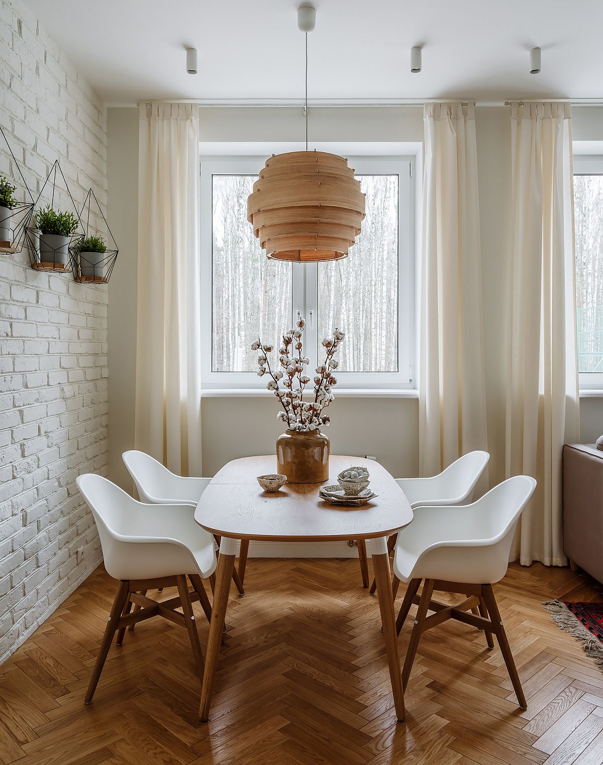 Dining room inside Moscow apartment with whitewashed brick wall, wooden floor and lovely white drapes