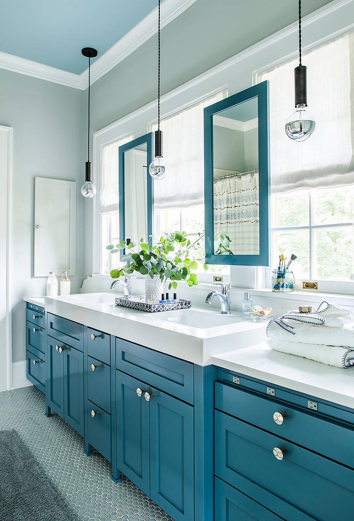 Gray bathroom with blue cabinets, mirror frames and ceiling