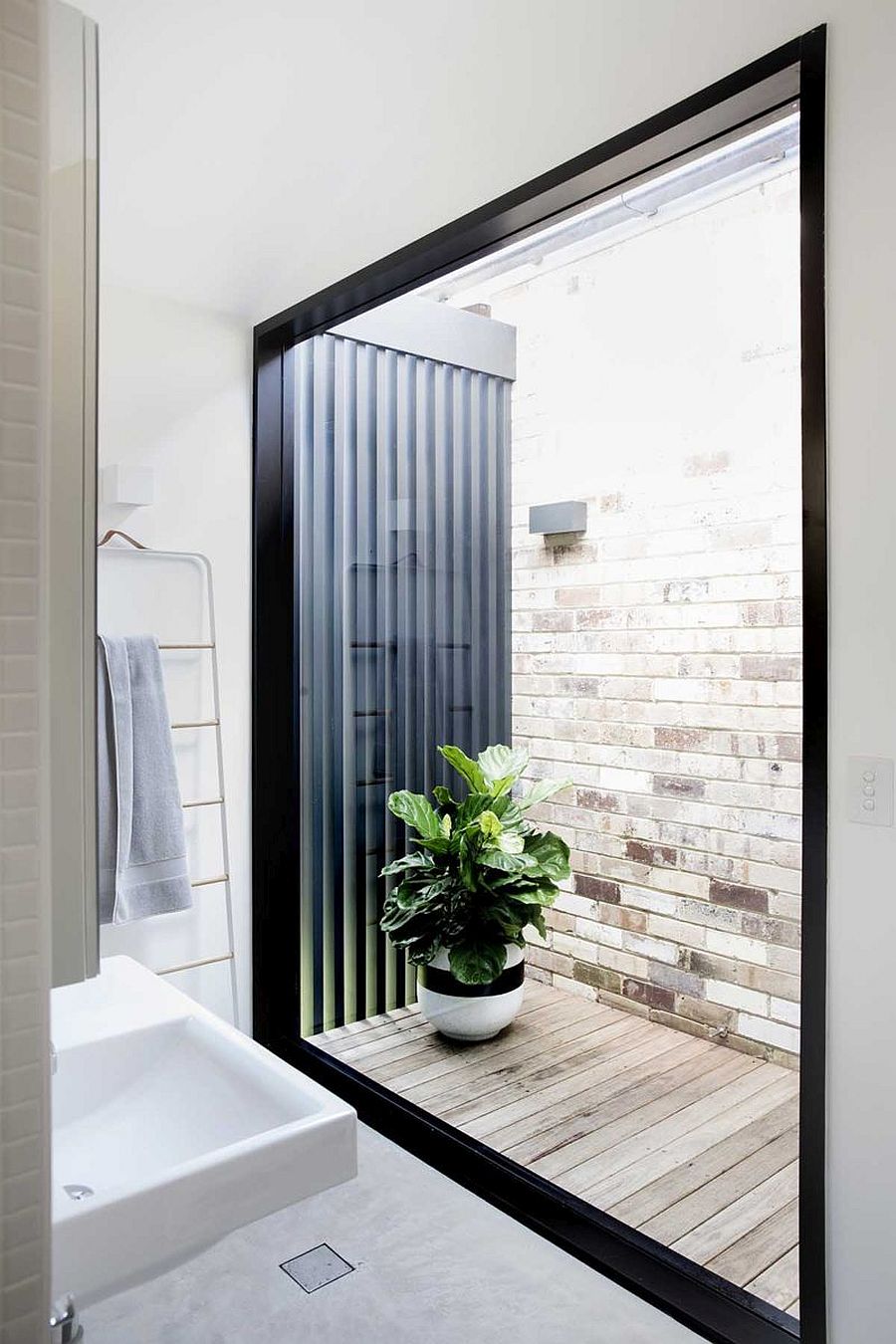 Large glass window brings light into the white bathroom