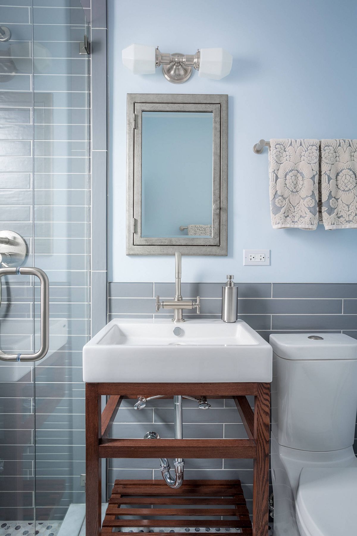 Modern gray and blue bathroom with small wooden vanity and lovely lighting