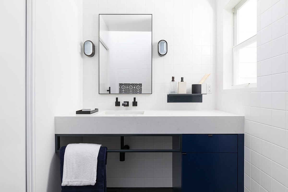 Bagno monocromatico in bianco con armadietti blu profondo e stile contemporaneo