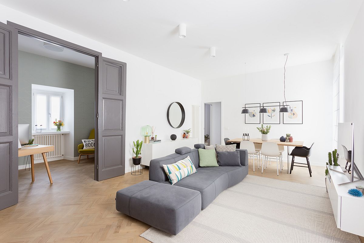 Open plan living area in white with Scandinavian style and large gray couch