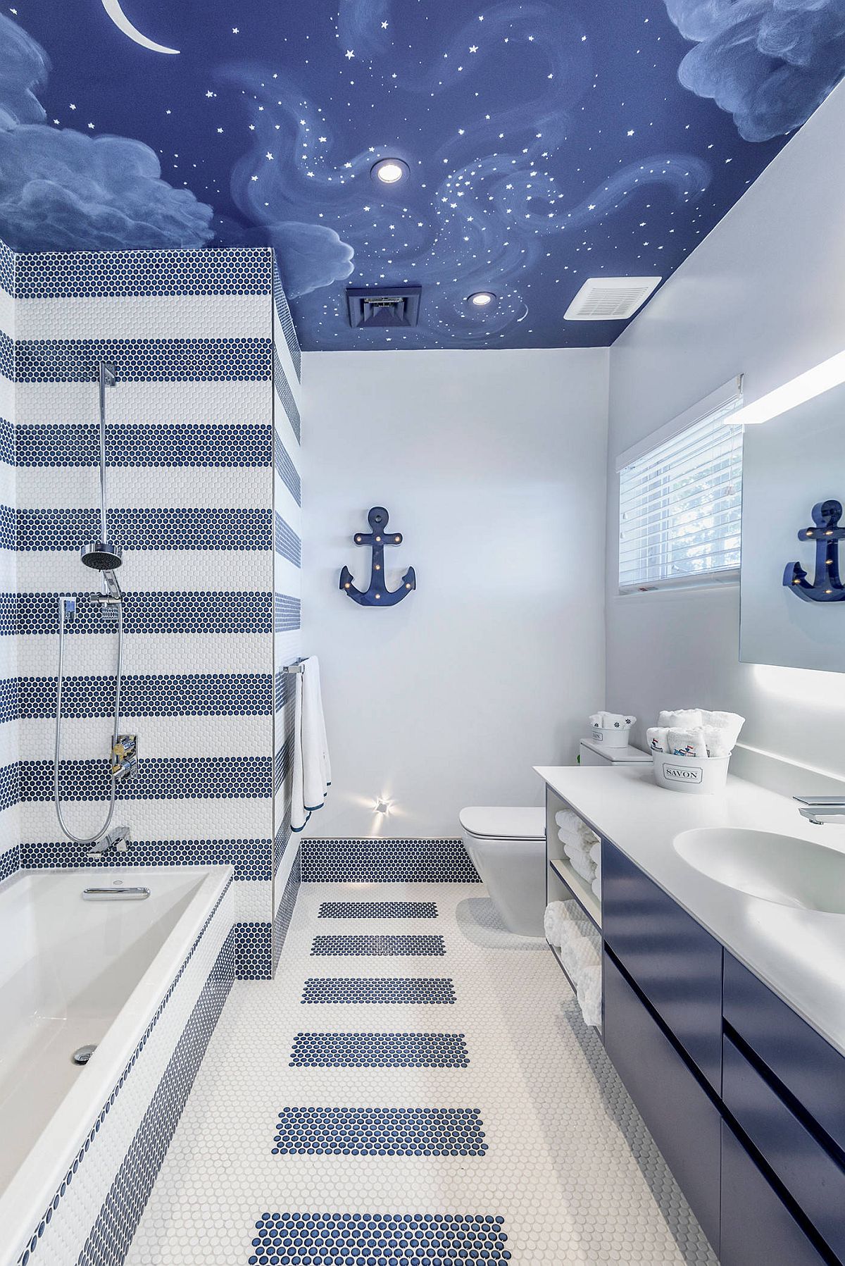 El techo pintado y el encantador uso de azulejos azules y blancos crean un elegante baño para niños#039; baño