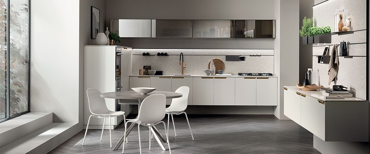 Refined modern kitchen in white with a white round dining table, chairs and upper shelves featuring translucent glass doors