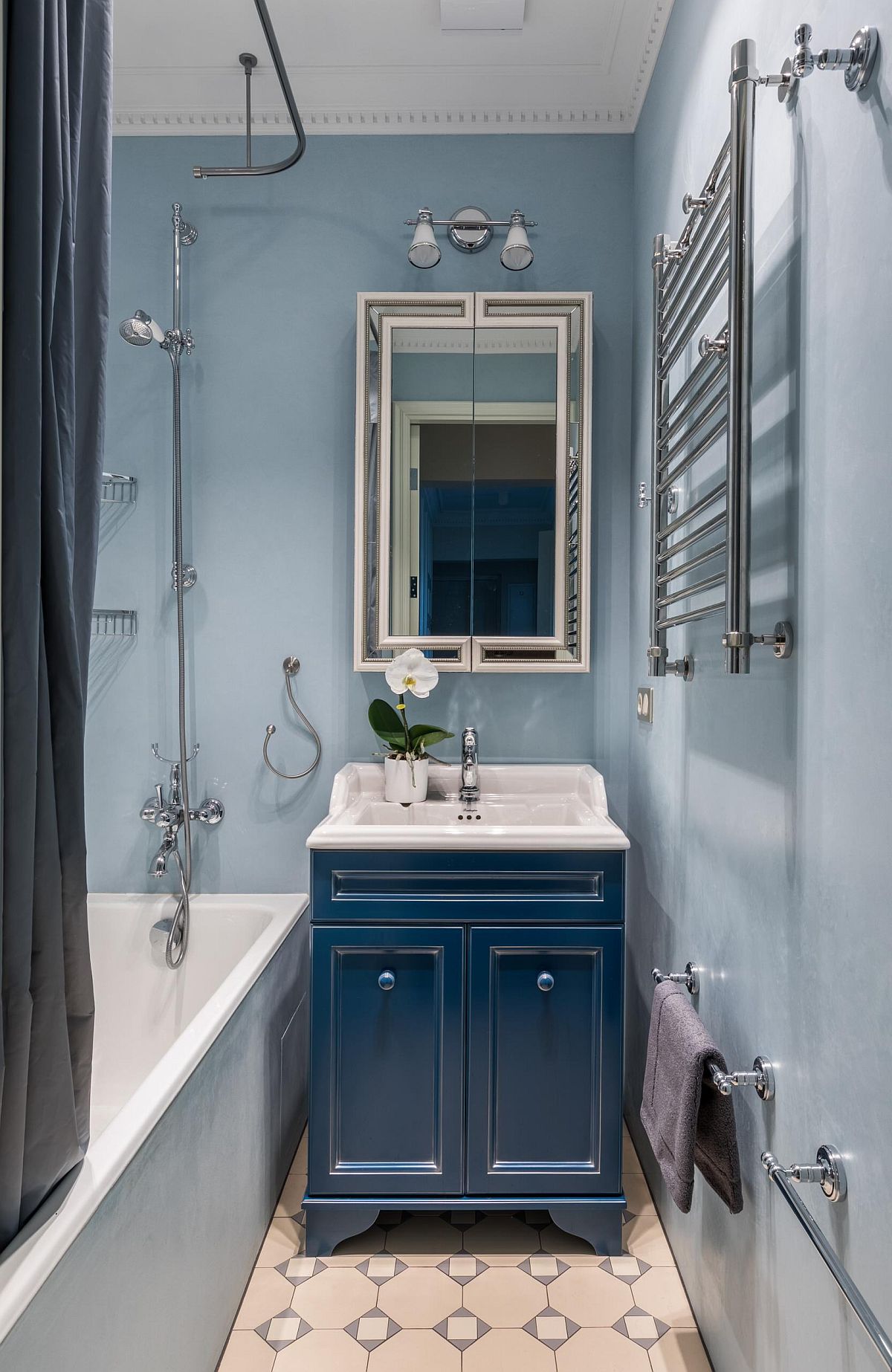 Small bathroom in light blue and white of Moscow home with a dark blue vanity and space-savvy design