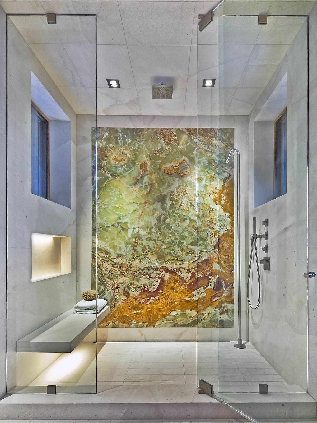 La spectaculaire toile de fond en Onyx de l'espace douche remplace les œuvres d'art murales traditionnelles. douche remplace l'art mural traditionnel dans cette salle de bain