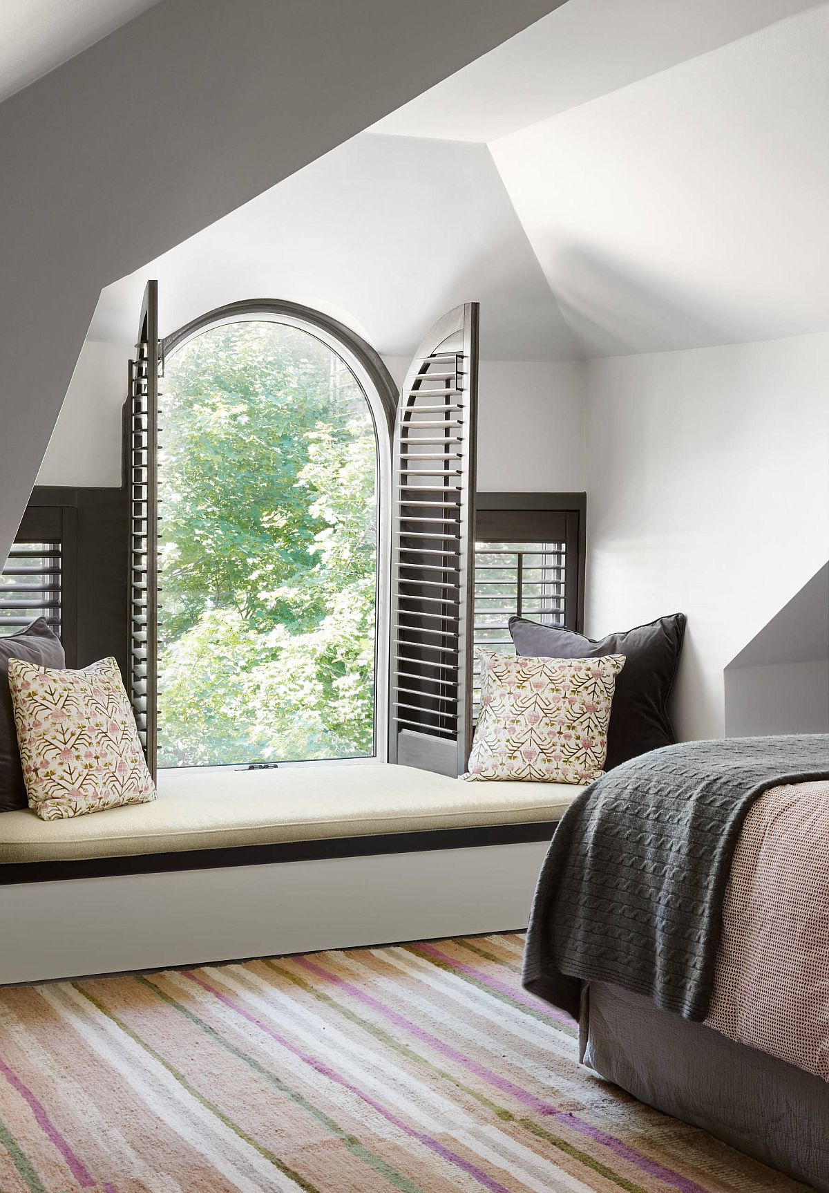Window seat coupled with arched window gives the modern bedroom traditional appeal