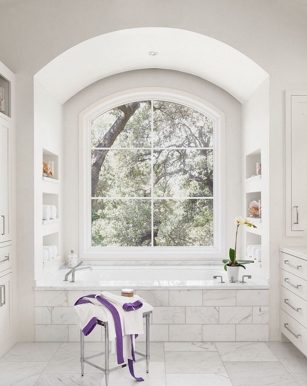 All white modern bathroom of the Texas home with a view of the leafy outdoors