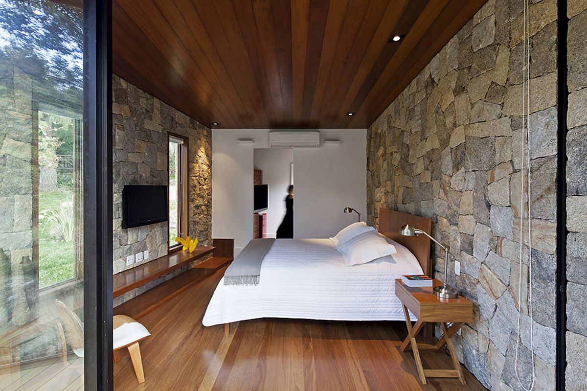 Bedroom of the retreat with stone walls, sliding glass doors and wooden flooring