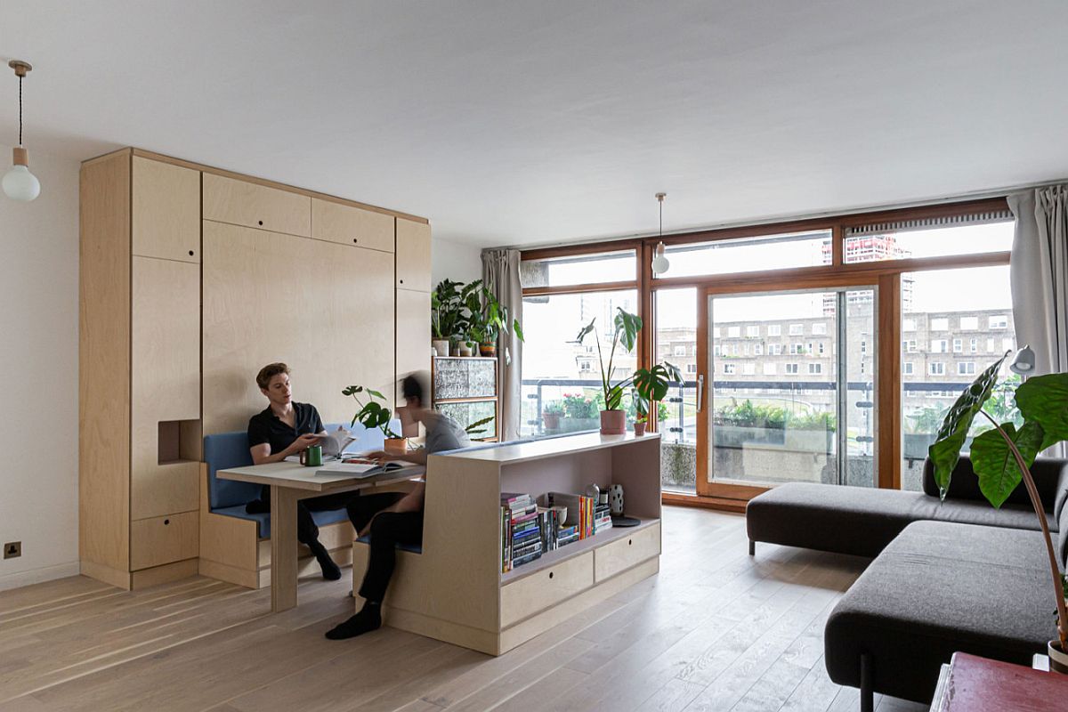 Bespoke wooden wall in the living room turns the same area into dining space, workspace and bedroom