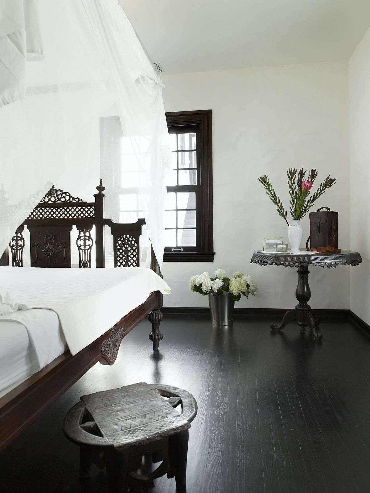 Black floors beautifully balance this dashing Mediterranean style bedroom in white with fabulous sheer curtains