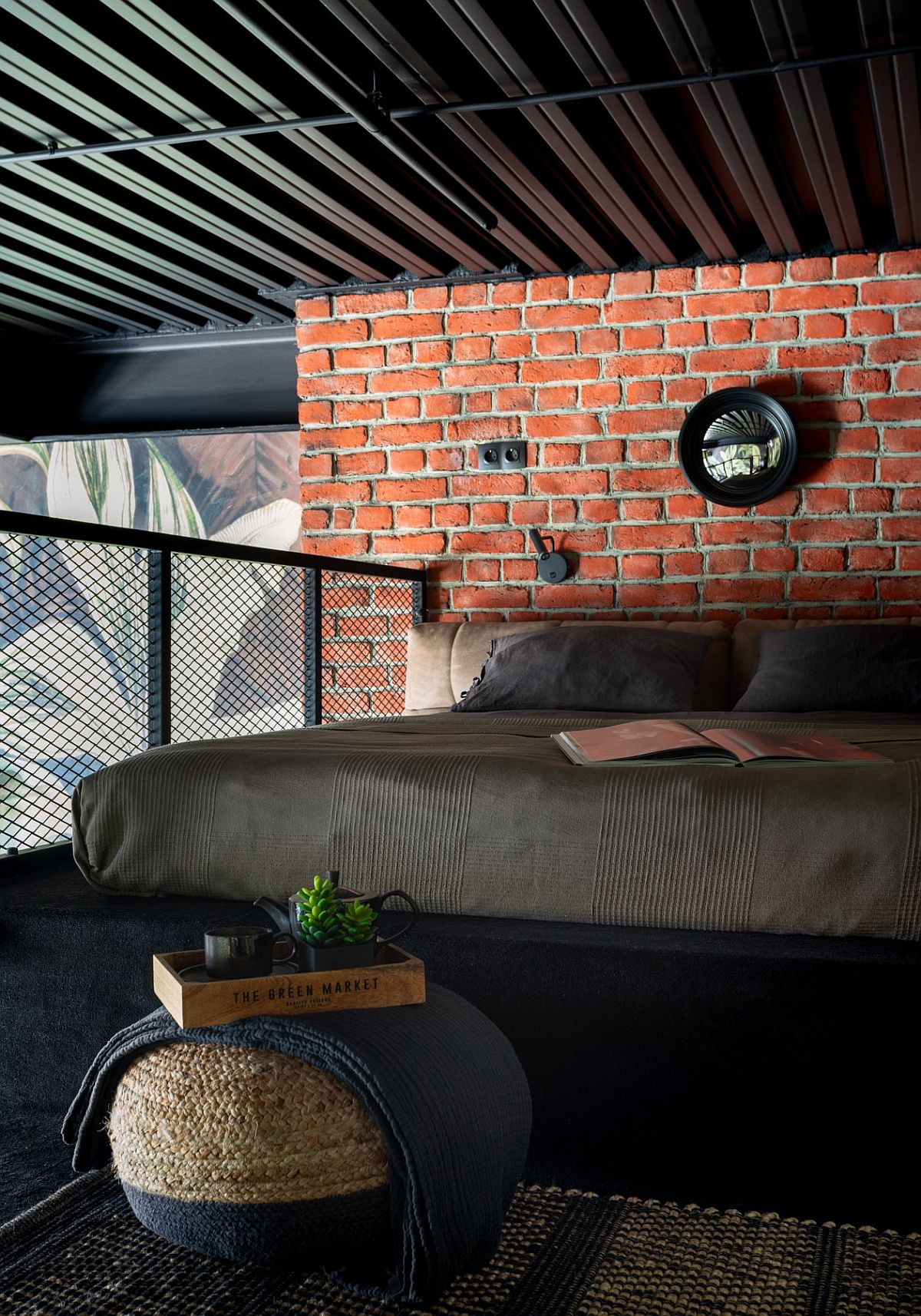 Brick wall and smart metal mesh offer ample textural contrast to this small industrial bedroom