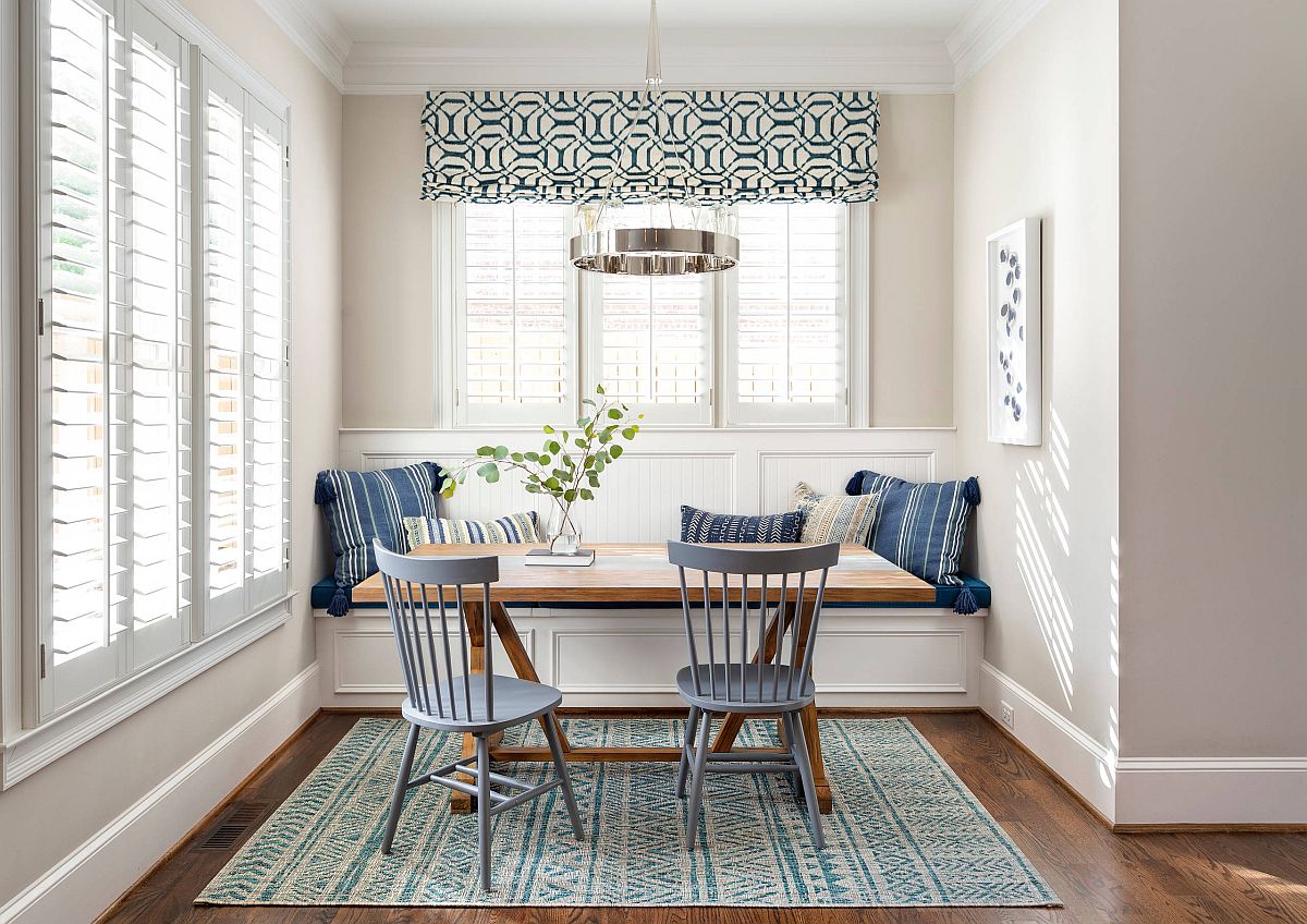 Chairs in bluish-gray and striped pillows bring color to this small beach style dining room